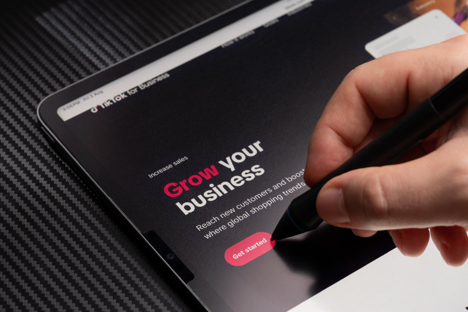 Tablet ekranında TikTok for Business reklam sayfası ve kalemle dokunan el