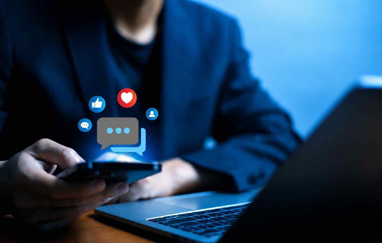 Telefonunu kullanan kişinin çevresinde beliren sosyal medya beğeni ve yorum ikonları
